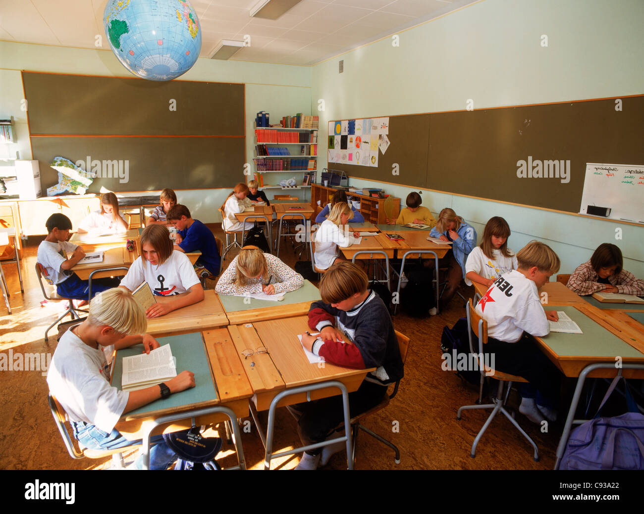 Les enfants de l'école élémentaire la lecture et l'écriture à un bureau en classe sous globe en Suède Banque D'Images