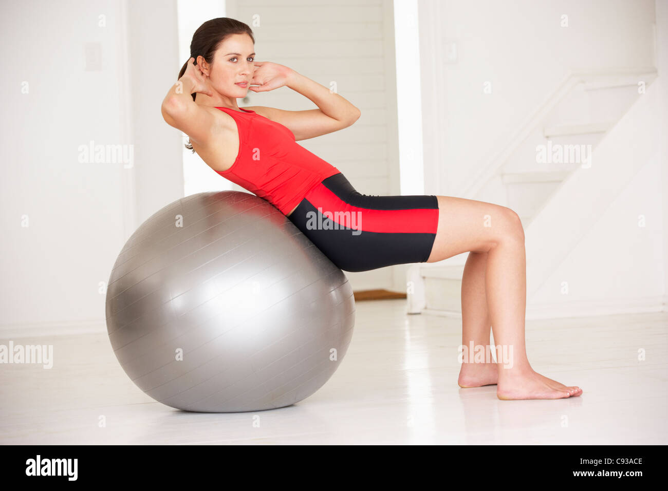 Femme avec ballon de gymnastique en salle de gym à domicile Banque D'Images