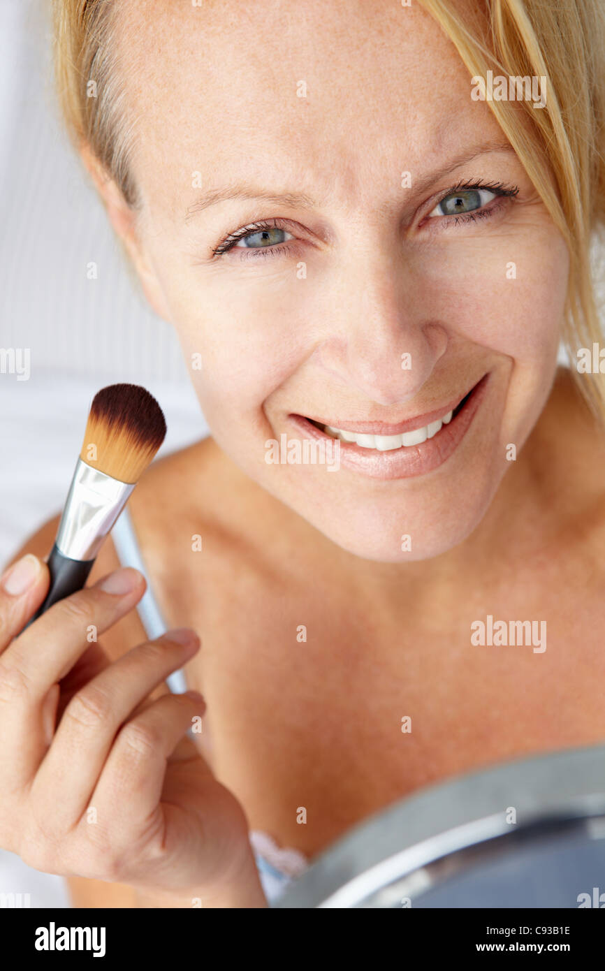 Mid age woman putting on make-up Banque D'Images