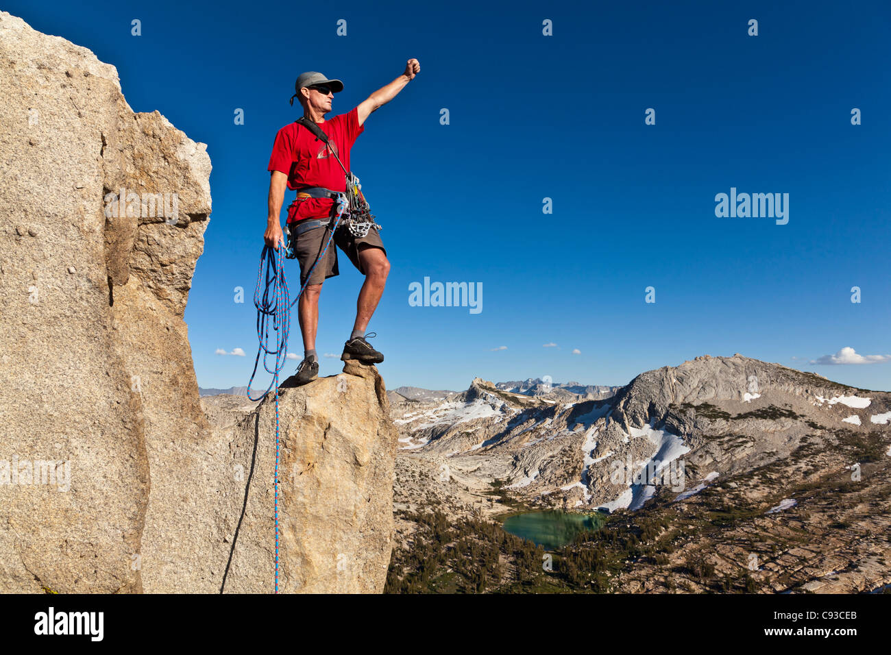 Male rock climber célèbre au sommet après une ascension réussie. Banque D'Images