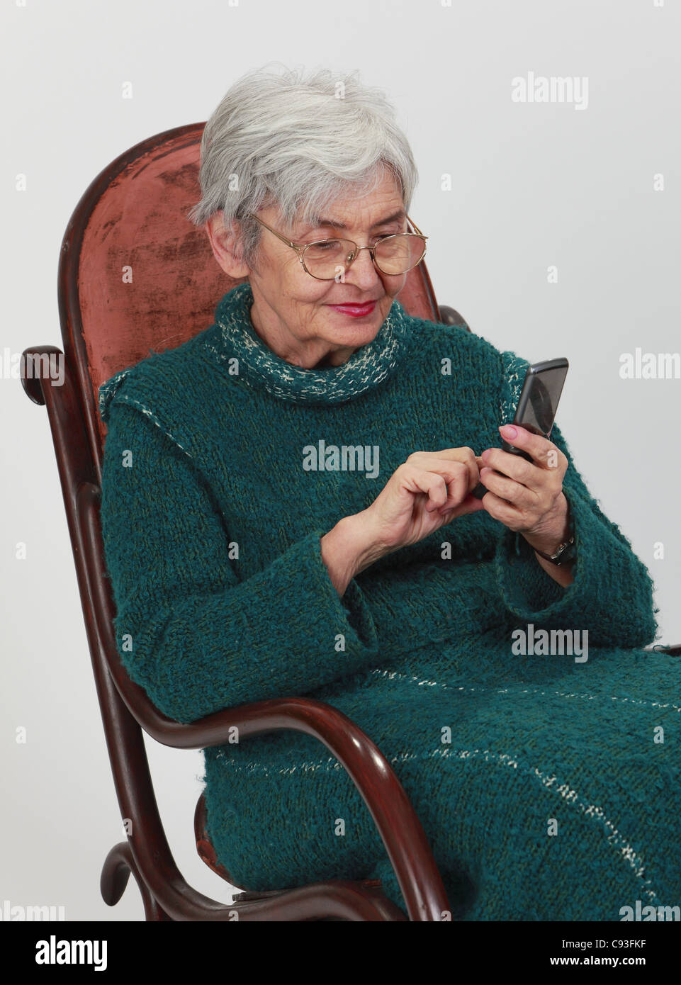 Close up image of a senior woman de l'emplacement dans un fauteuil à bascule et l'écriture d'un message téléphonique. Banque D'Images