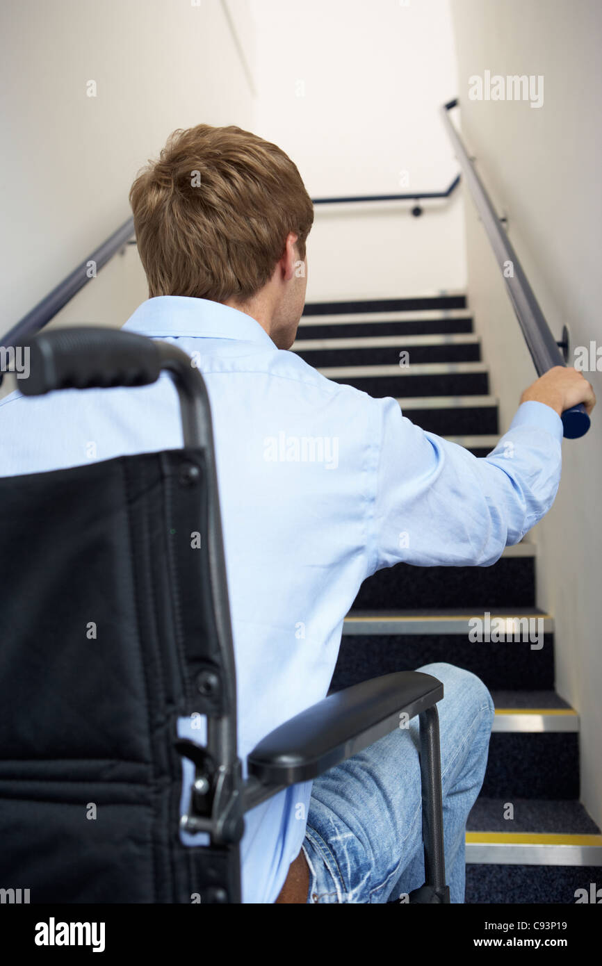 L'homme en fauteuil roulant à pied des escaliers Banque D'Images