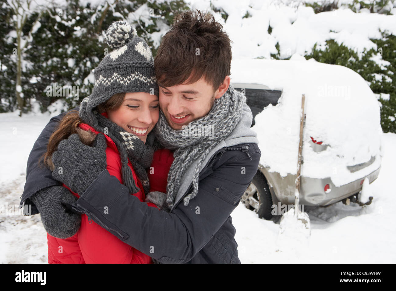 Jeune couple dans la neige avec voiture Banque D'Images