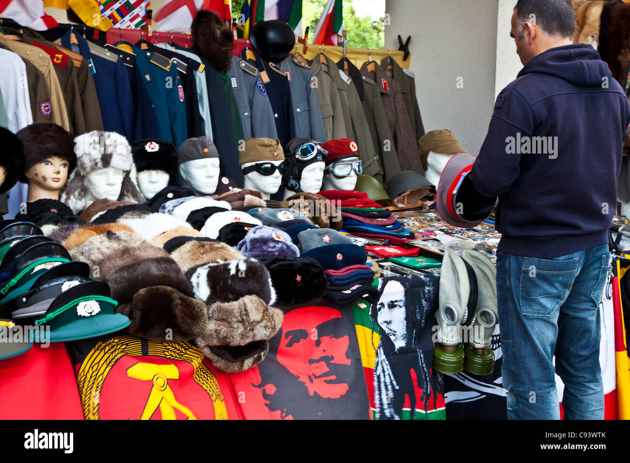 Un mâle'inspecte un chapeau et des uniformes militaires en temps de guerre et de souvenirs sur un étal de souvenirs touristiques à Berlin, Allemagne Banque D'Images