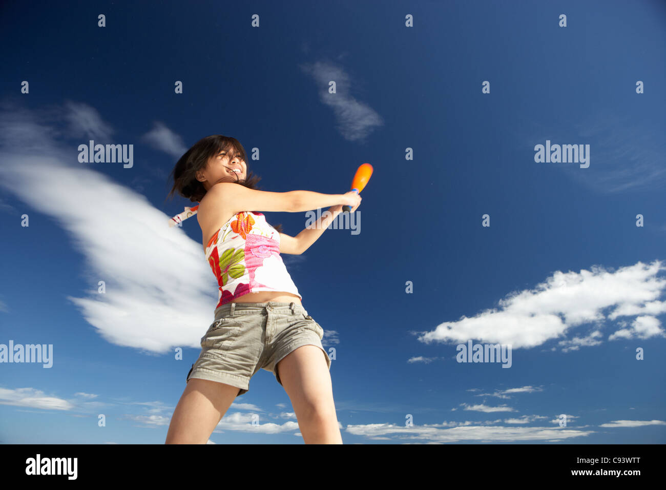 Teenage girl playing baseball on beach Banque D'Images