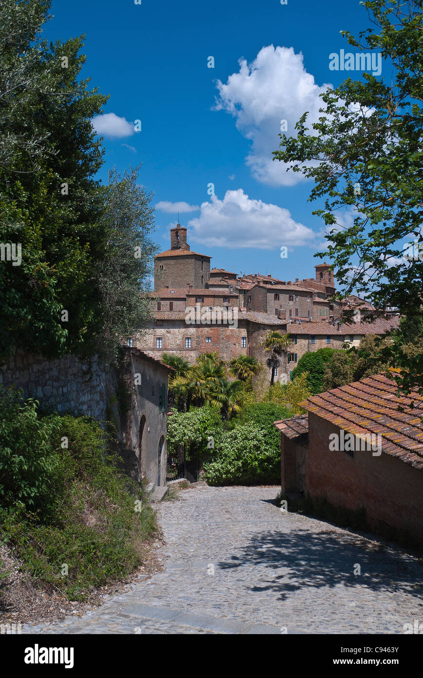 Vue à distance, à travers des arbres, des lignes de toit en tuiles rouges, de maisons et de deux tours de la ville médiévale fortifiée de Lucca, Italie. Banque D'Images