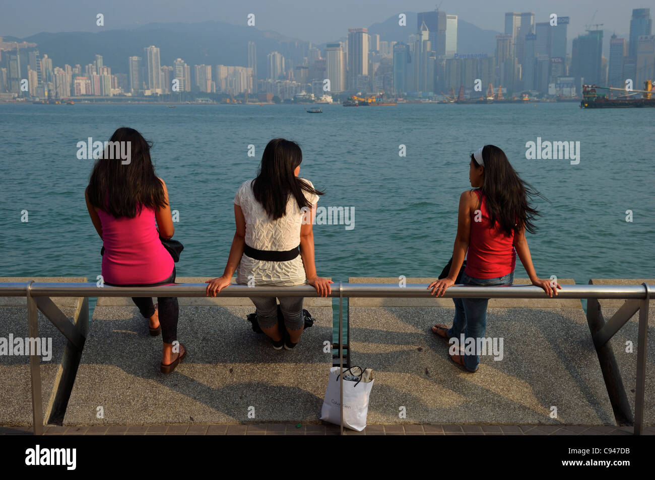 Trois filles Philippine bénéficiant d'une vue sur le port au quai de Kowloon, Hong Kong, Chine SAR Banque D'Images