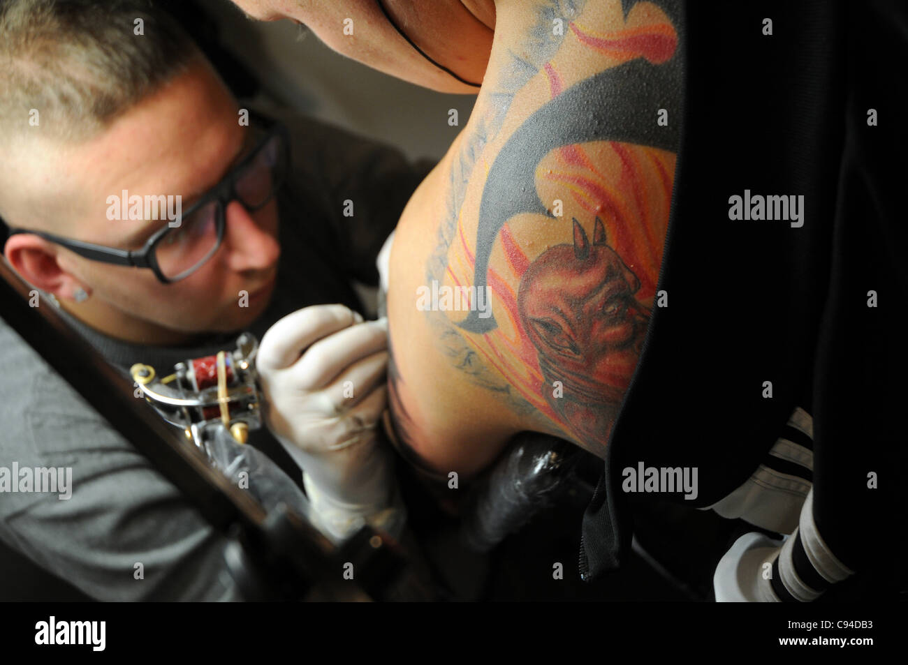 12.11.2011 Varsovie, Pologne. Tatoueur travaille avec son client au cours de la première journée de tattoo, body painting et pierceing show - Body Art 'Convention' dans un palais de la Culture et de la science à Varsovie. Banque D'Images