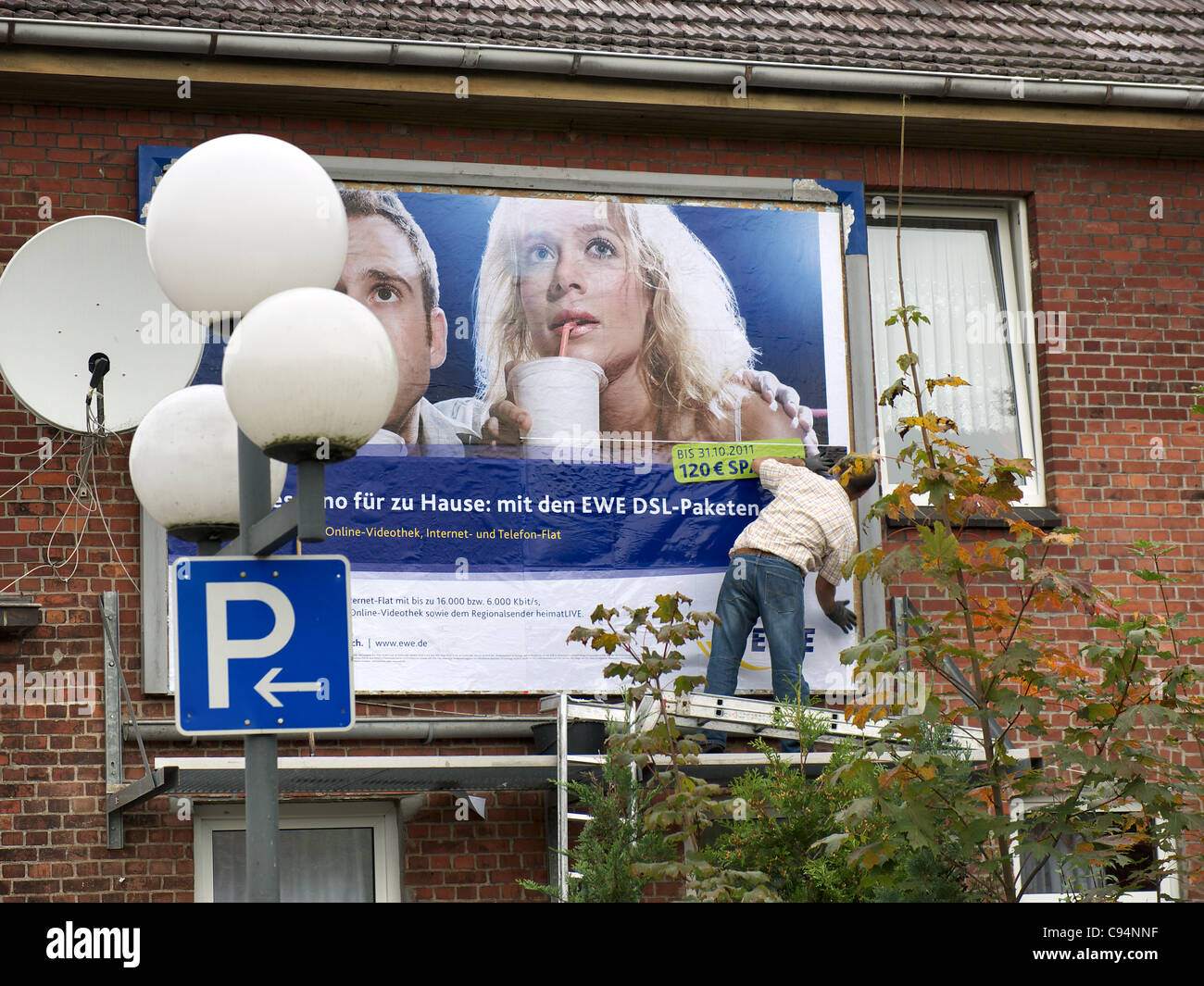 Billsticker travaillant dans un panneau sur une maison de Winsen-Luhe, Basse-Saxe, Allemagne. Banque D'Images