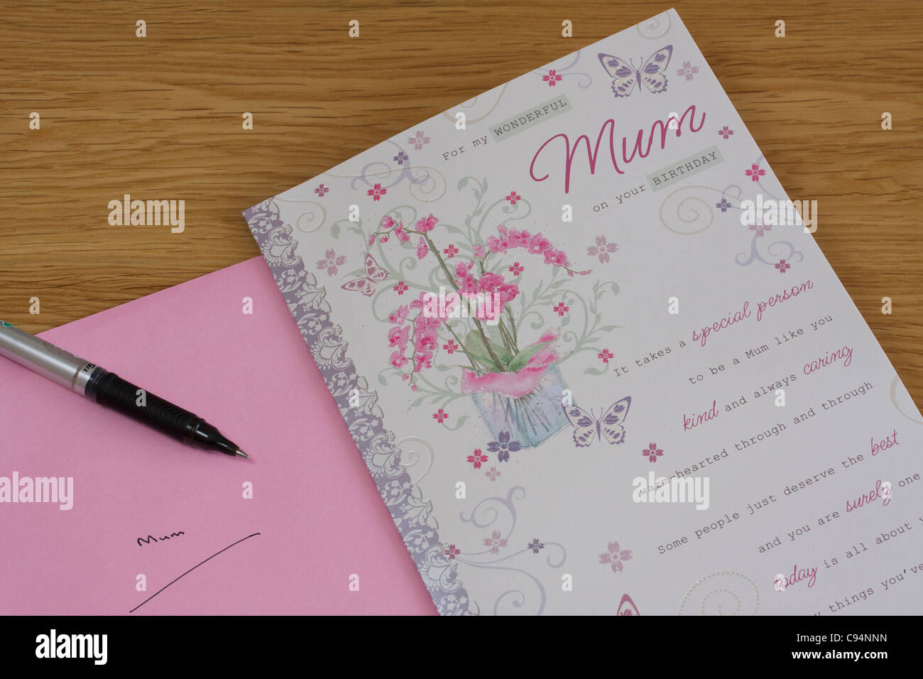Carte d'anniversaire, un stylo et enveloppe rose contre l'arrière-plan de table en bois pour maman. Aussi l'enveloppe a mot maman part écrit. Banque D'Images