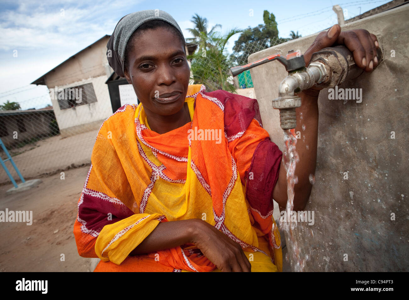 Une femme remplit un seau d'eau à un puits communautaire à Dar es Salaam, Tanzanie, Afrique de l'Est. Banque D'Images