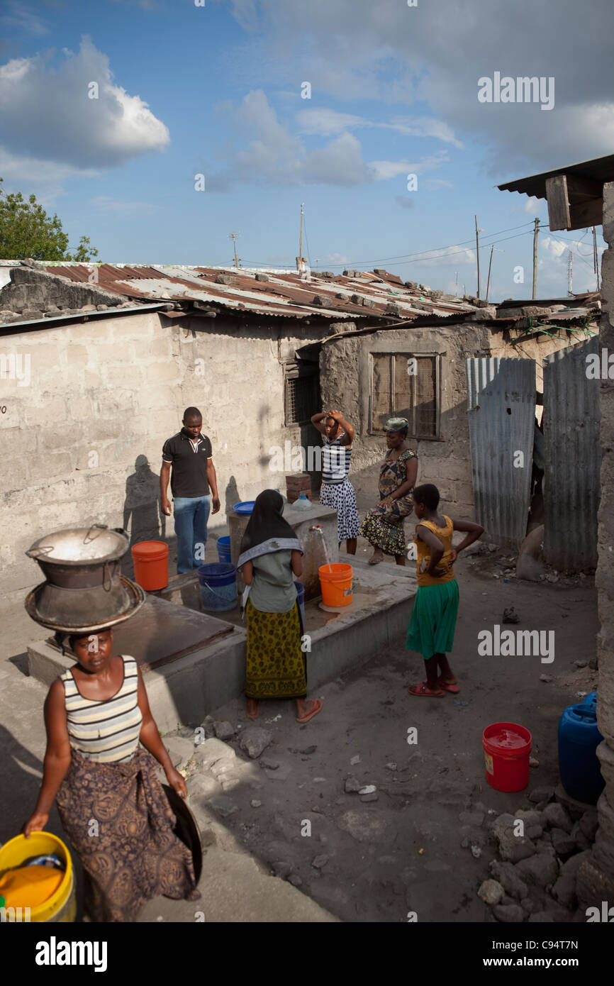 Keko Mwanga, résidents d'un bidonville à Dar es Salaam, Tanzanie, Afrique de l'Est, de recueillir l'eau d'un robinet dans la communauté. Banque D'Images