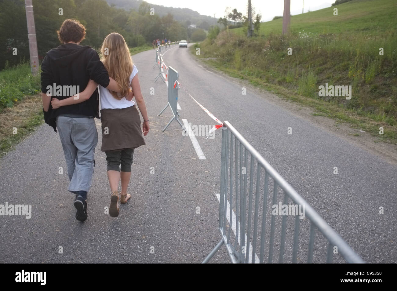 Couple en train de marcher le long de la route pendant le festival Kumpania, musiques des Balkans, dans d'Argein, Ariège, France. Banque D'Images