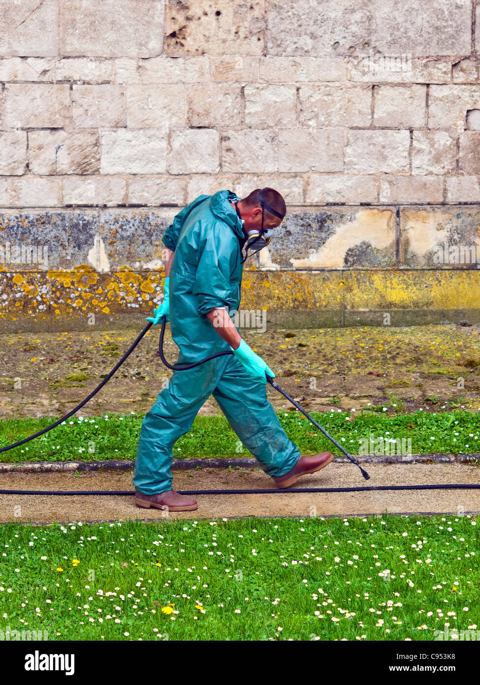 Travailleur en salopette de protection et masque de pulvériser les mauvaises herbes - France. Banque D'Images