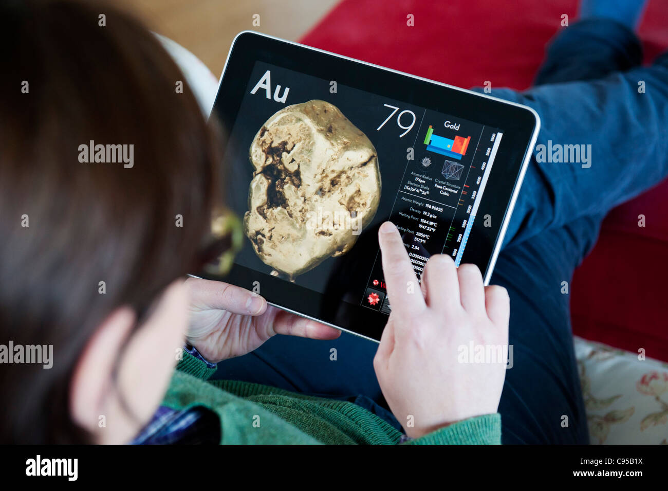 Femme à l'aide de l'ordinateur tablette iPad pour étudier la chimie de l'or à l'aide de l'application des sciences de la table périodique Banque D'Images