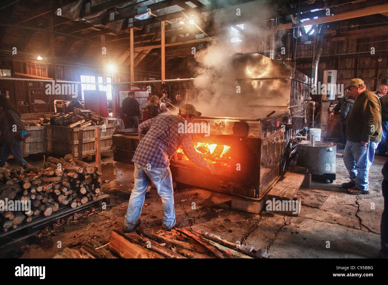 Un travailleur stokes l'incendie de Gould's sugar house Banque D'Images