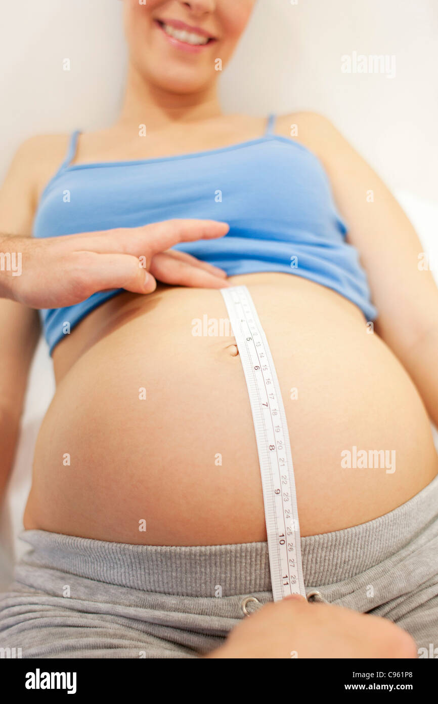 Examen obstétrique. Sage-femme lors de la mesure d'une femme enceinte est de l'abdomen, un centre de naissance. Banque D'Images