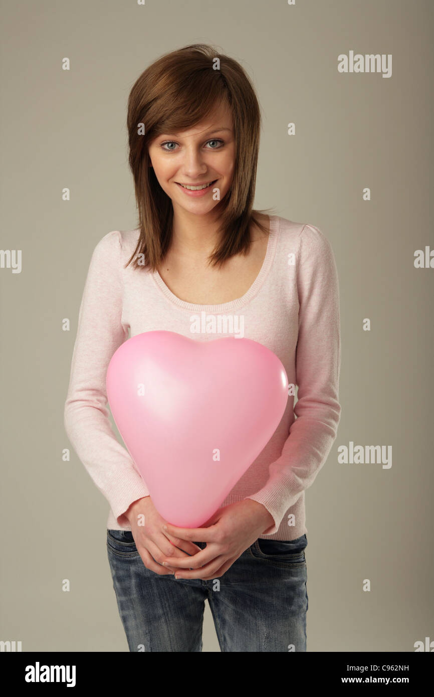 Pretty woman holding a pink balloon en face d'elle. Banque D'Images