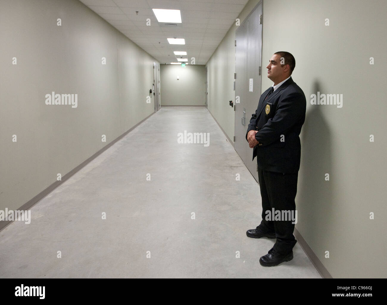 Male Hispanic security guard est seul dans le couloir vide de l'Electric Reliability Council of Texas (ERCOT) Banque D'Images