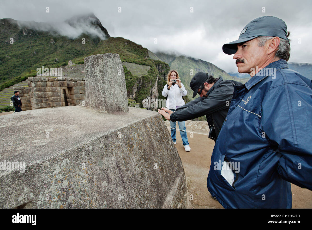 Gardien de sécurité regardant Intihuatana autel de pierre à l'ancienne ruines Incas de Machu Picchu, site touristique populaire dans la région des Andes. Banque D'Images