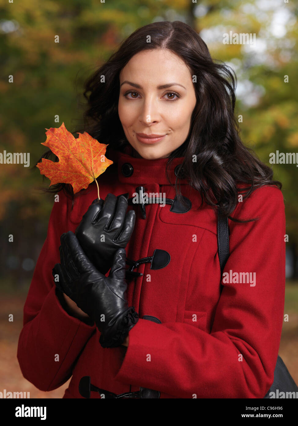 Portrait d'une belle femme tenant une feuille d'érable rouge dans ses mains Banque D'Images