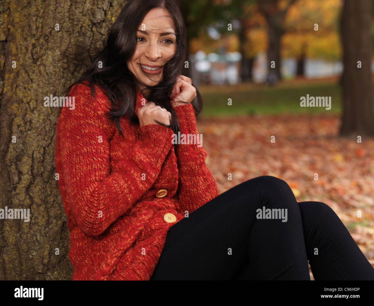 Beautiful smiling woman cuddling up dans un chandail rouge. Couvrant de vent dans l'automne. Banque D'Images