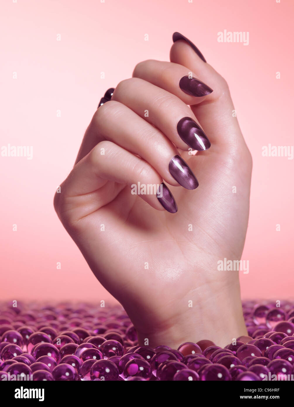 Licence disponible à MaximImages.com gros plan de la main de la femme avec vernis à ongles violet sortant d'une mer de bonbons Banque D'Images