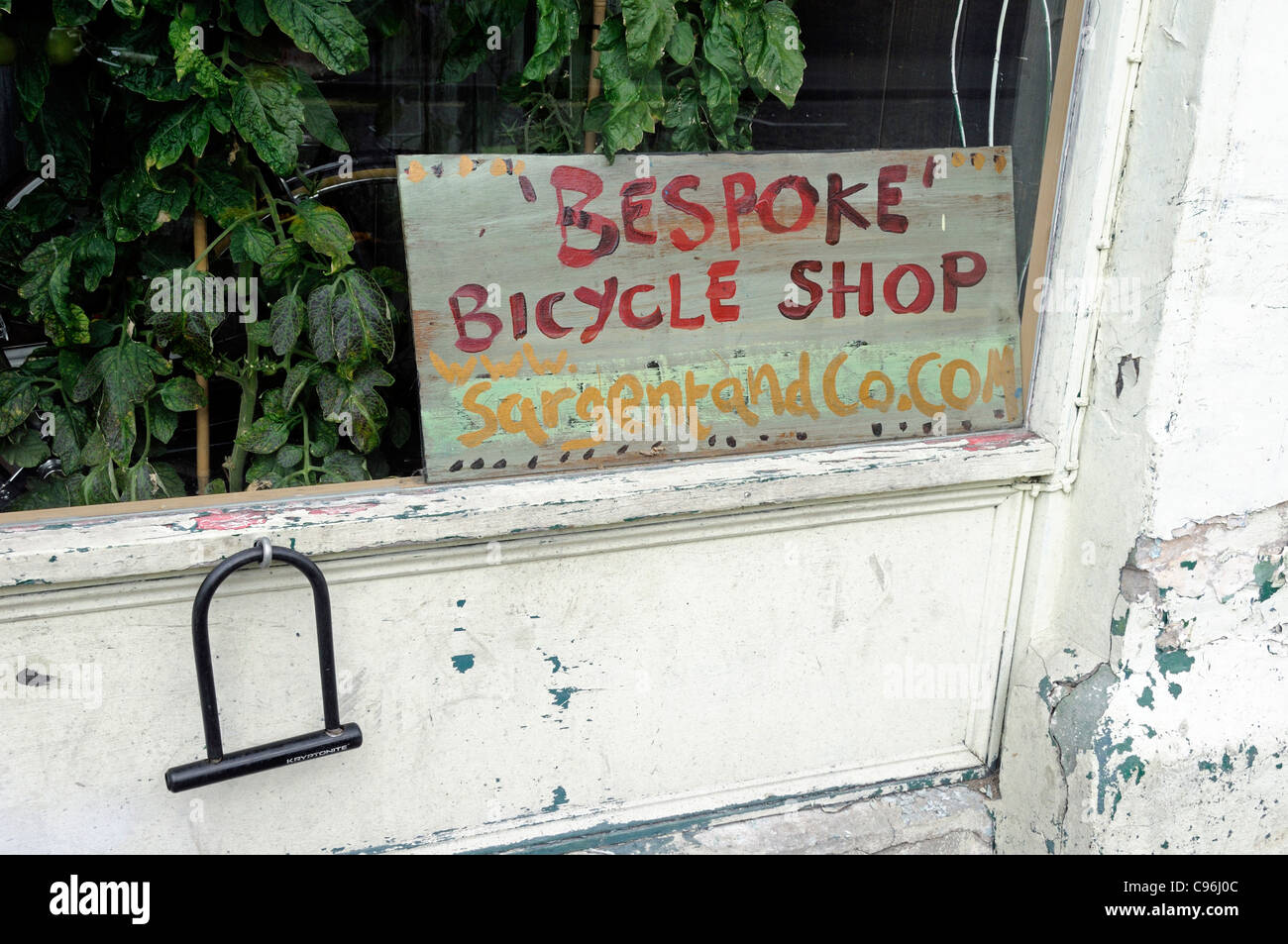 Panneau disant 'Bespoke' Bicycle Shop au coin de vitrine avec u lock pendant de mur à l'extérieur, Sargent et co, Hackney Banque D'Images