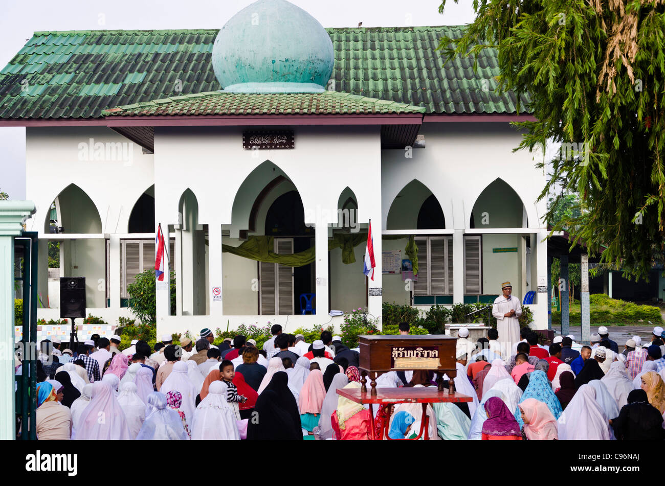 Mosquée avec un service religieux en plein air en session. Des dizaines de personnes assises sur le sol en robe musulmane dans le nord de la Thaïlande Banque D'Images