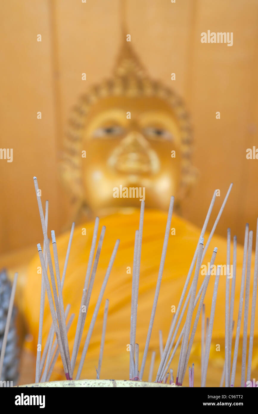 Libre de joss stick d'une statue du Bouddha Phra Yot temple au derrière, Huay Yot, Thaïlande Banque D'Images