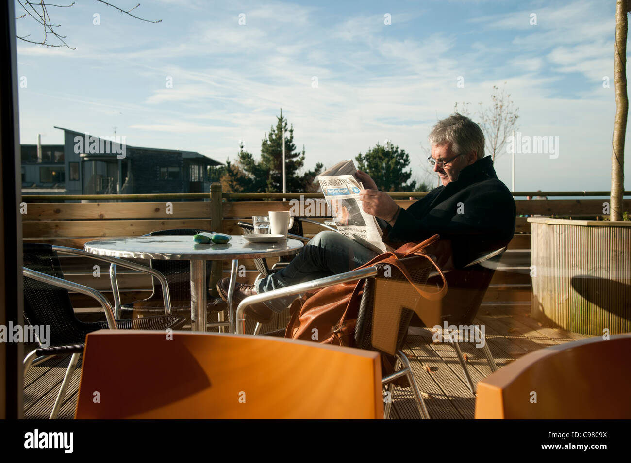 Un homme d'âge moyen de la lecture d'un exemplaire du journal The Times à un café en plein air, UK Banque D'Images