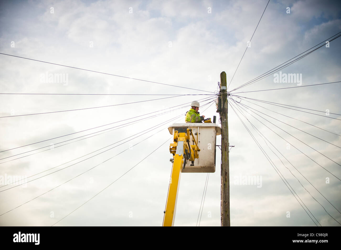 Un BT British Telecom engineer repairing une ligne téléphonique à partir d'une plate-forme surélevée, UK Banque D'Images