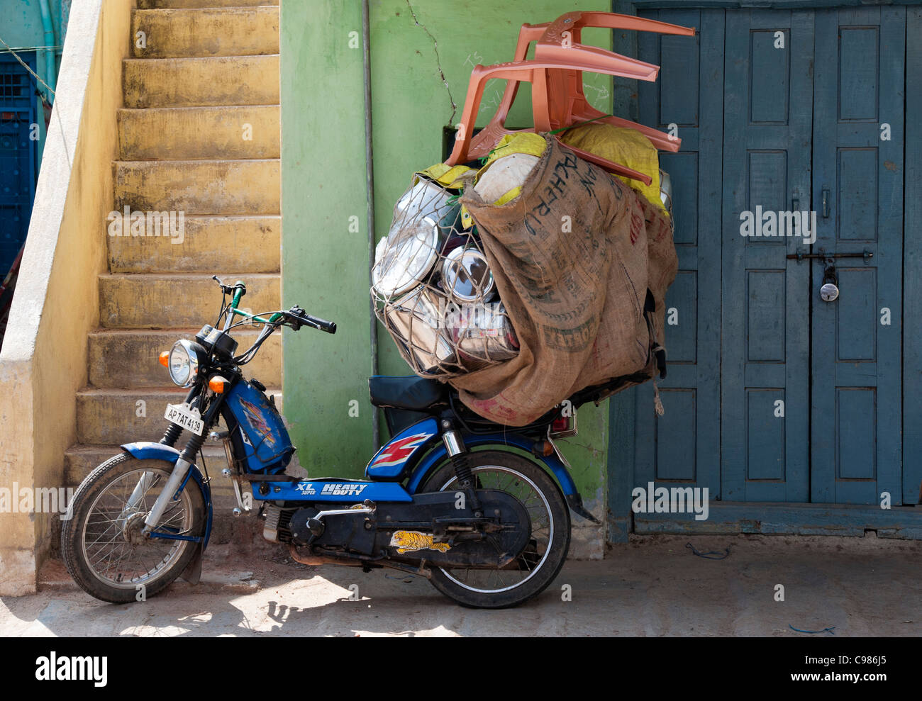 Cyclomoteur ladened indiennes avec des marchandises à vendre à des magasins locaux dans les rues de Puttaparthi, Andhra Pradesh, Inde Banque D'Images