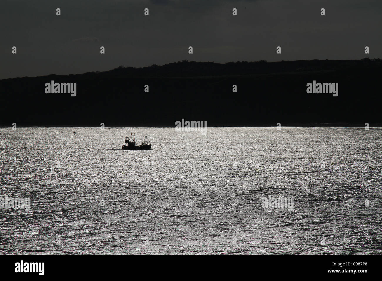 Bateau de pêche de retourner à Harbour en silhouette. Banque D'Images