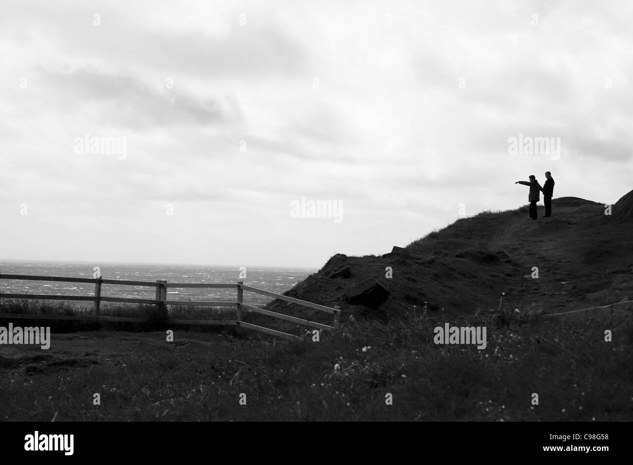 Photo en noir et blanc de 2 personnes, l'une dirigée, et donnant sur l'océan Atlantique à Cape Spear, à Terre-Neuve, Canada. Banque D'Images