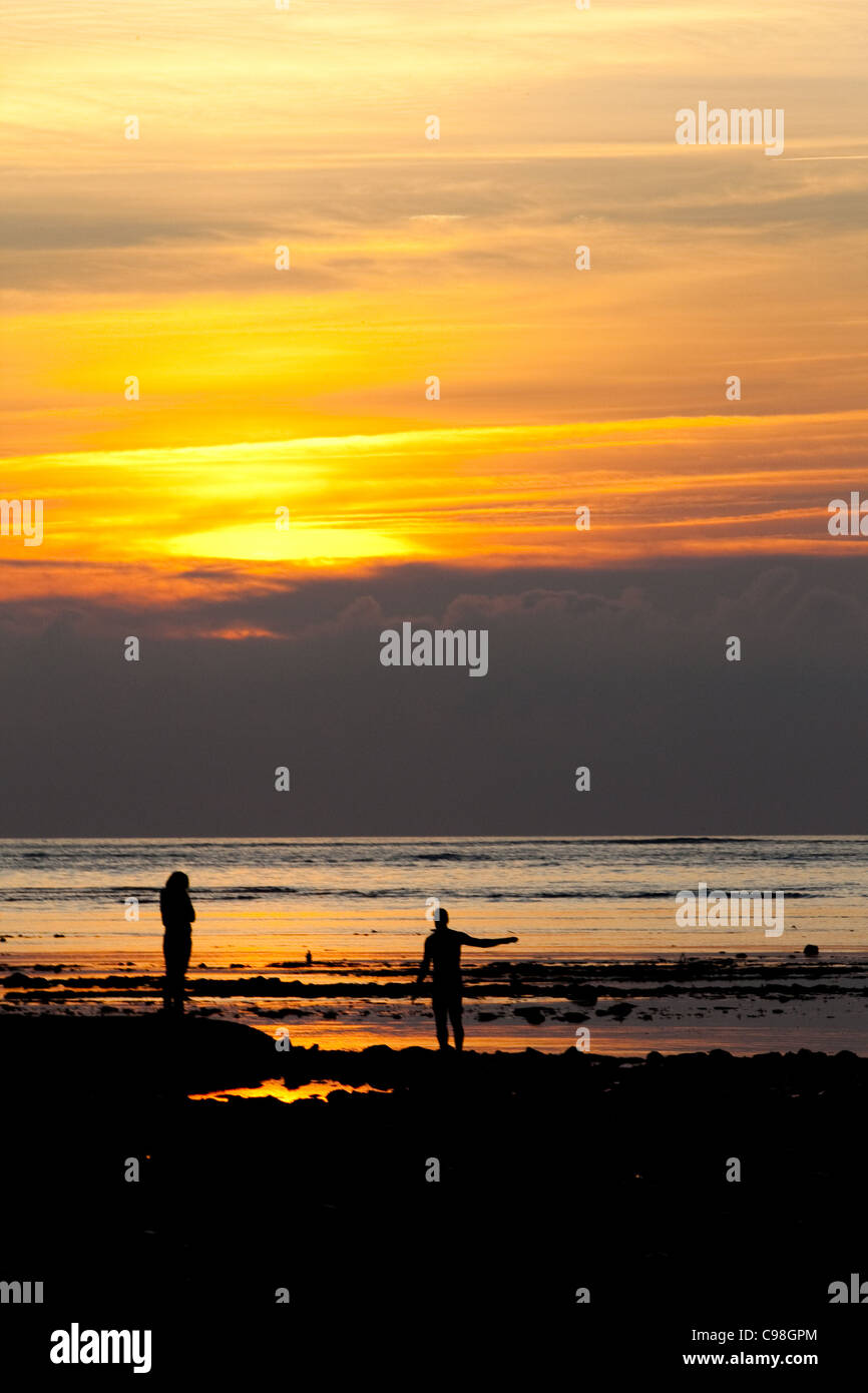 Coucher du soleil vertical silhouette de deux personnes à la recherche de l'océan Atlantique au large de l'île de Ré en France. Banque D'Images