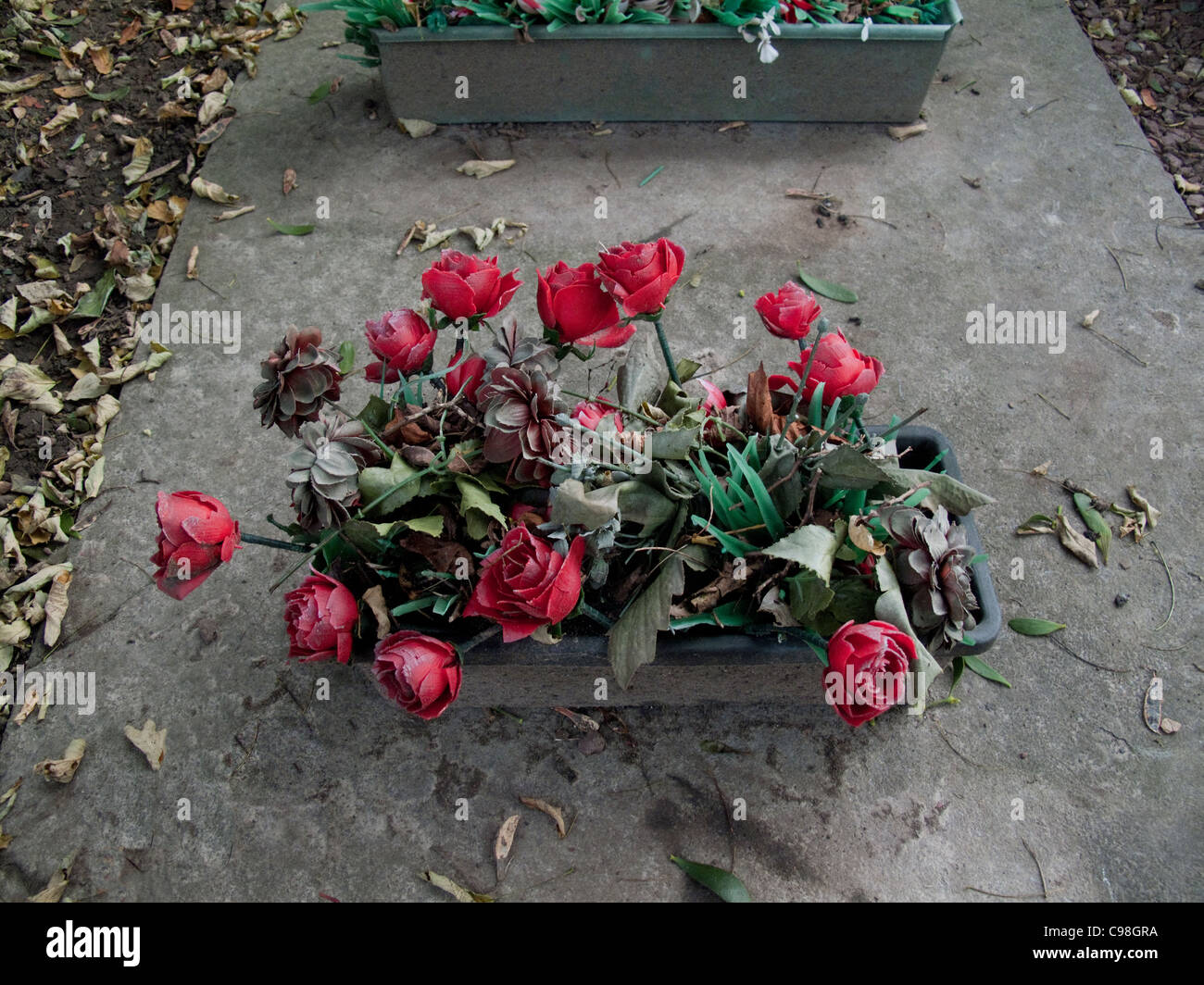 Fleurs en plastique rouge pâle sur la tombe. Banque D'Images