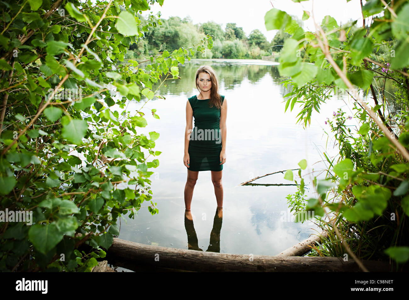 Jeune femme robe vert, lac permanent Banque D'Images