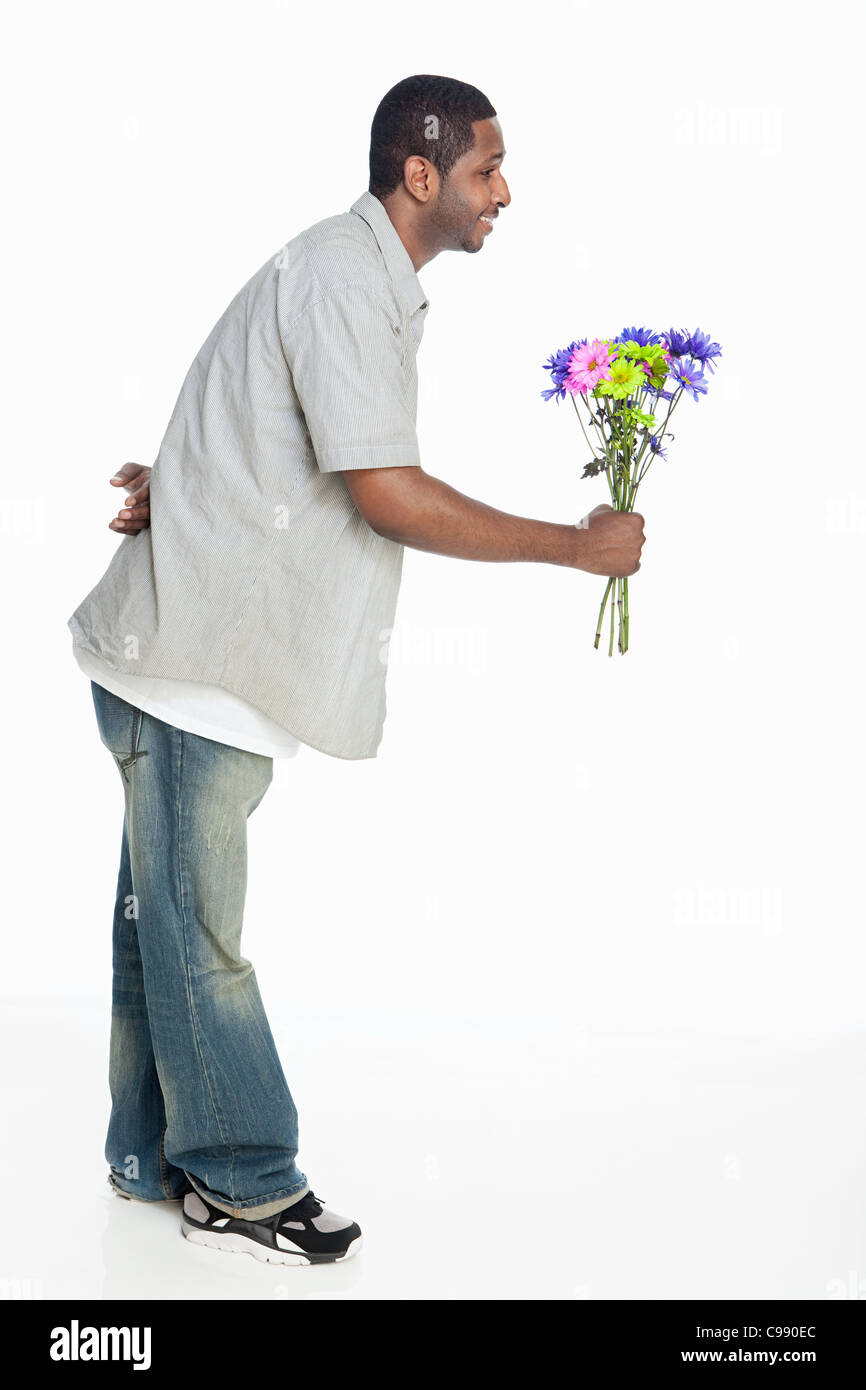 Mid adult man giving flowers against white background Banque D'Images
