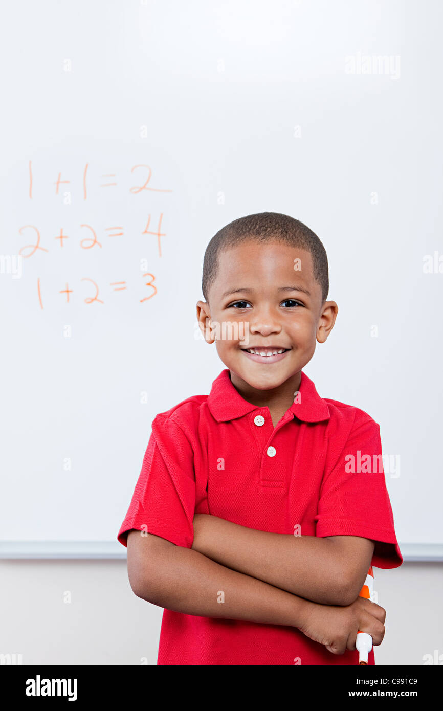 Écolier heureux en face de mathématiques sur tableau blanc Banque D'Images