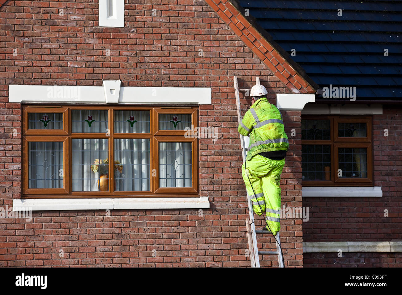 Les hommes sur grimper aux échelles  bille de polystyrène house l'isolation des murs creux, les travailleurs dans les harnais de sécurité, l'installation de l'isolation en mousse à Southport, Royaume-Uni Banque D'Images
