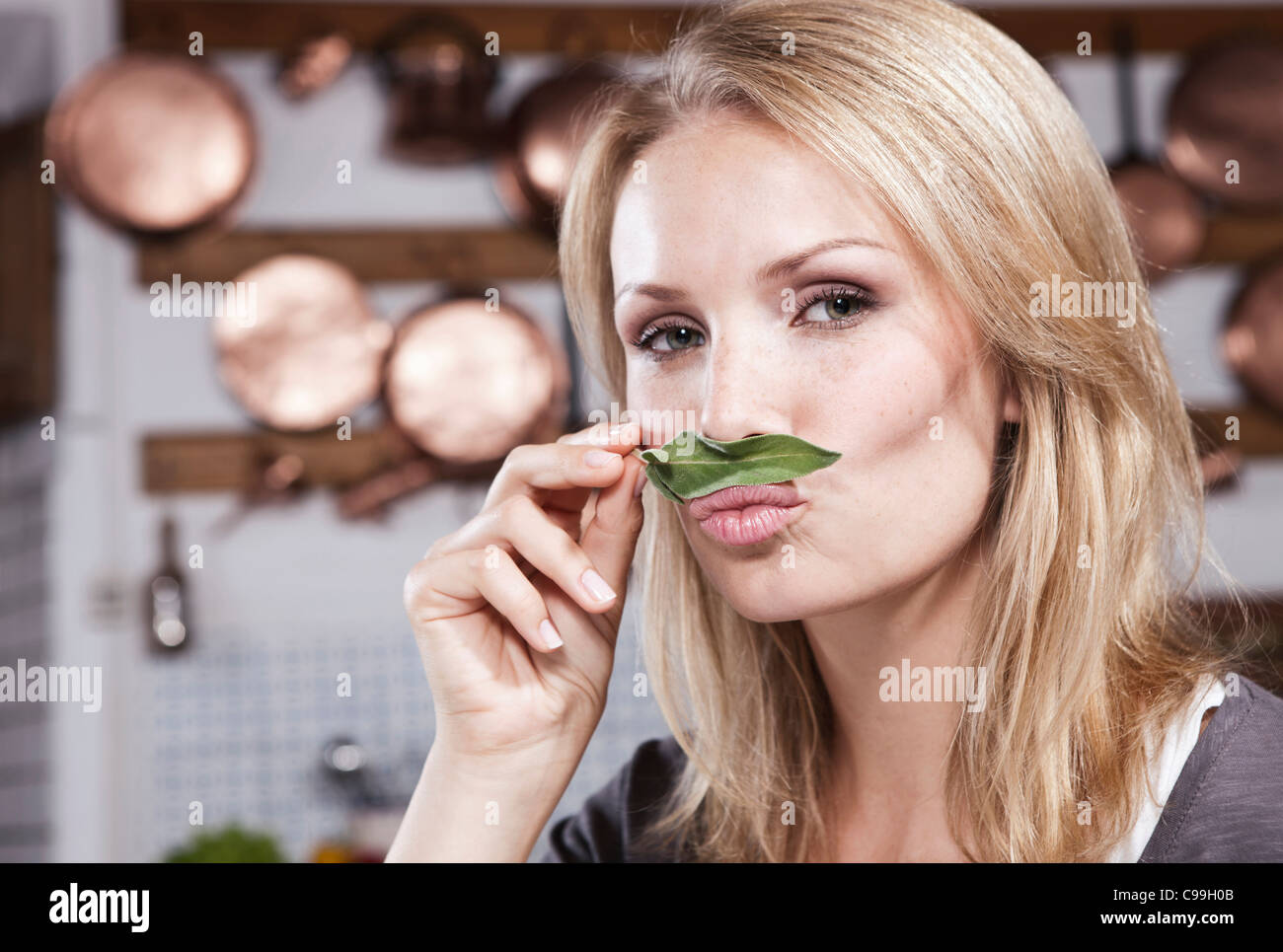Italie, Toscane, Magliano, Close up of young woman smelling feuille de basilic en cuisine, portrait Banque D'Images