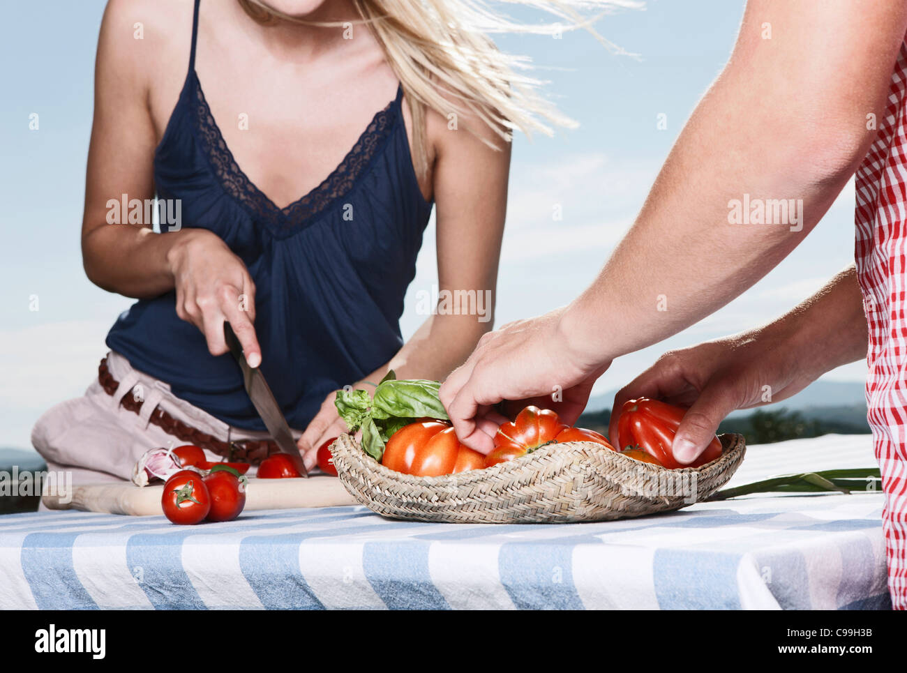 Italie, Toscane, Magliano, jeune homme debout près de la table et coupe femme tomates, smiling Banque D'Images