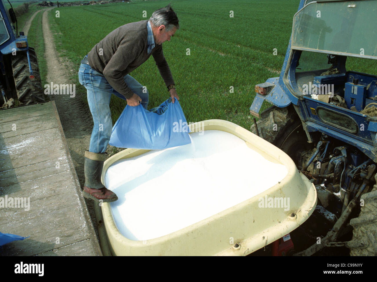 Farmer monté sur tracteur de remplissage trémie d'engrais avec l'engrais azoté (ICI) MIB Fashion Banque D'Images