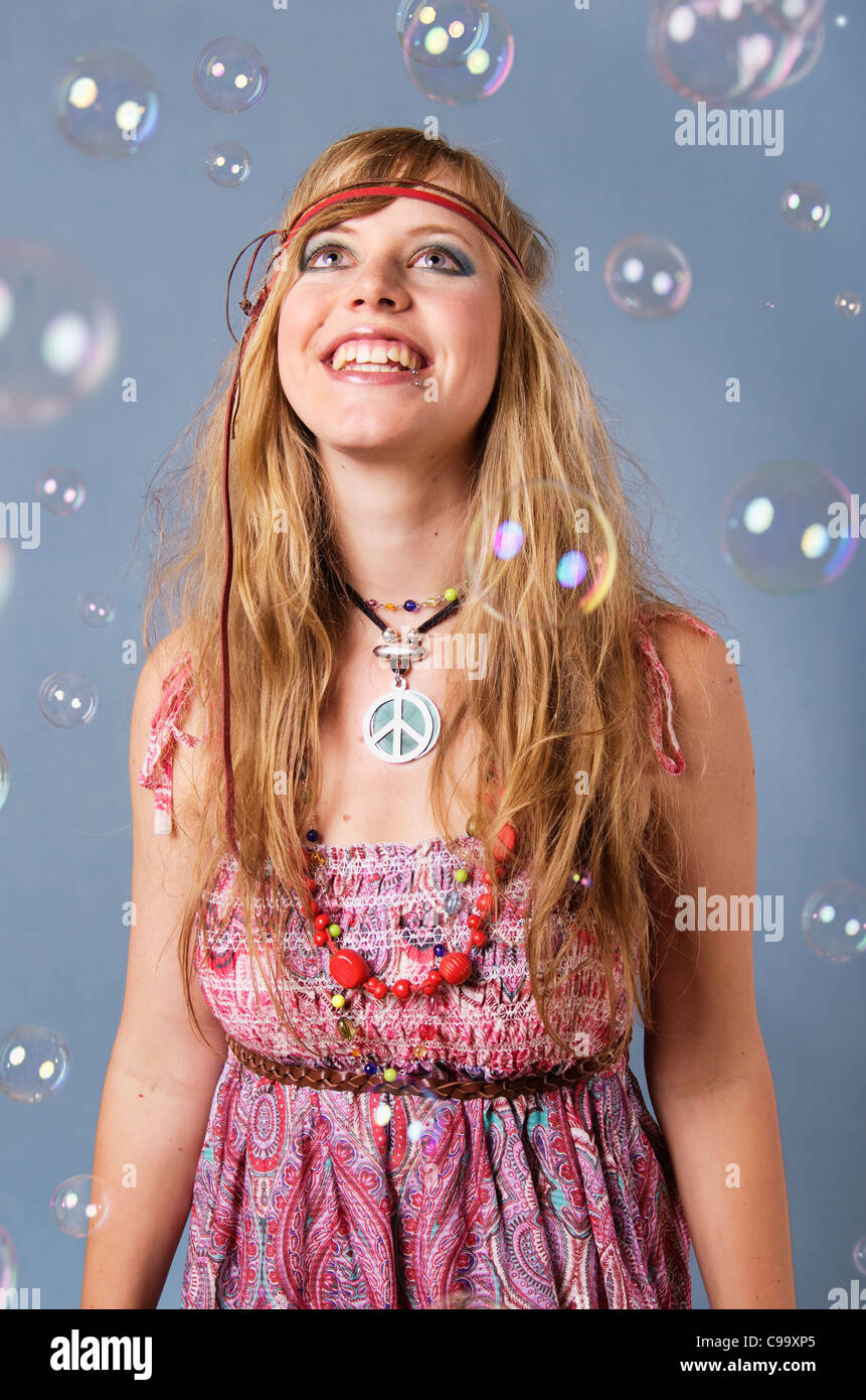Jeune femme hippie avec bulles contre l'arrière-plan gris, smiling Banque D'Images