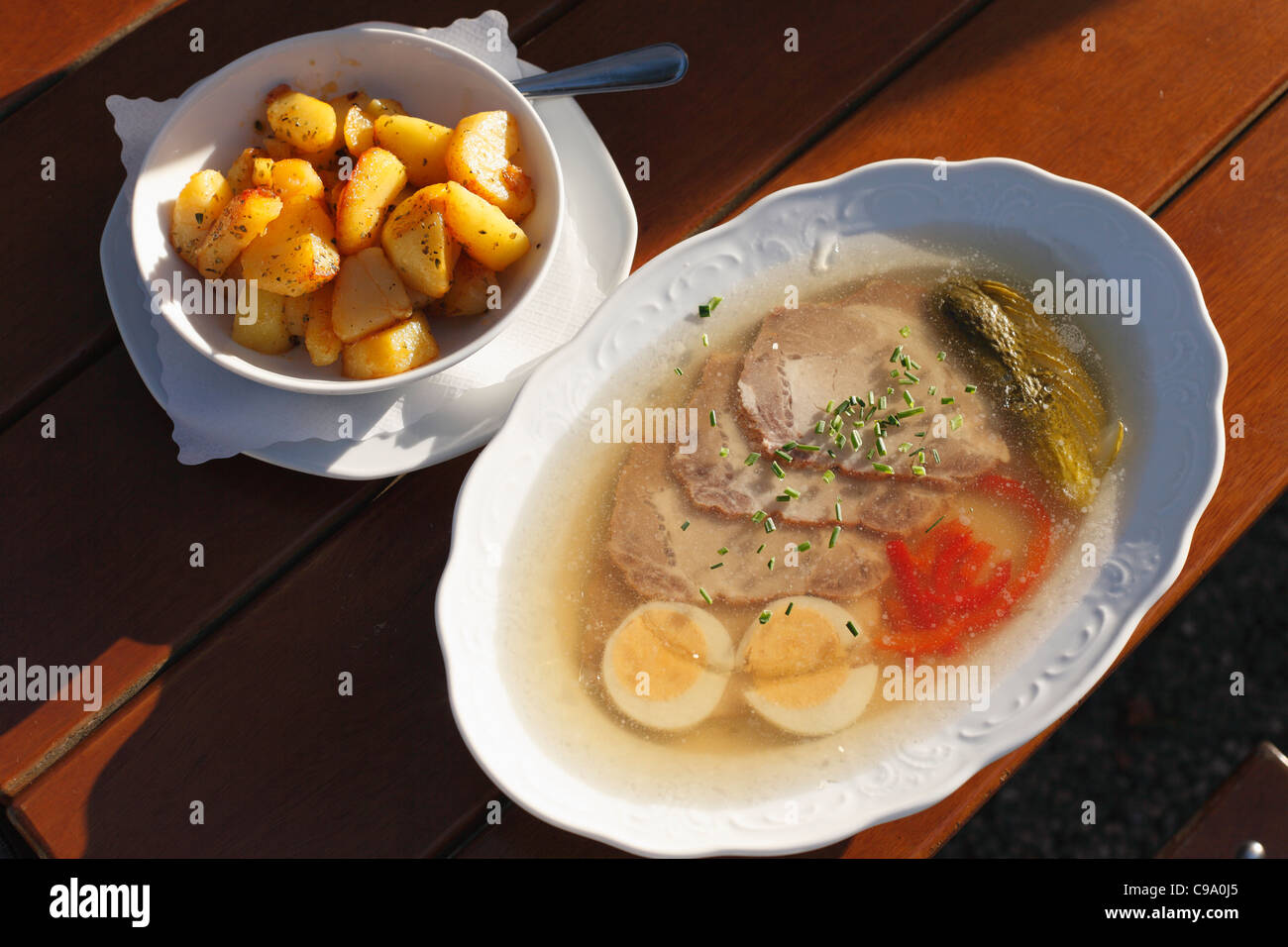 Germany, Bavaria, Murnau, Close up d'aspic rôti et pommes de terre rissolées sur table en bois Banque D'Images