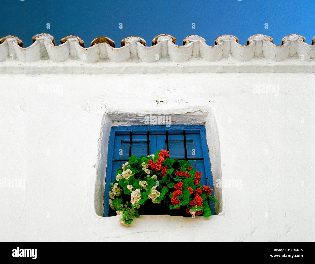 Une fenêtre d'hiver fort de fleurs en plastique à la fenêtre d'une maison de village traditionnelle - Torrox Costa, Malaga, Andalousie, Espagne Banque D'Images