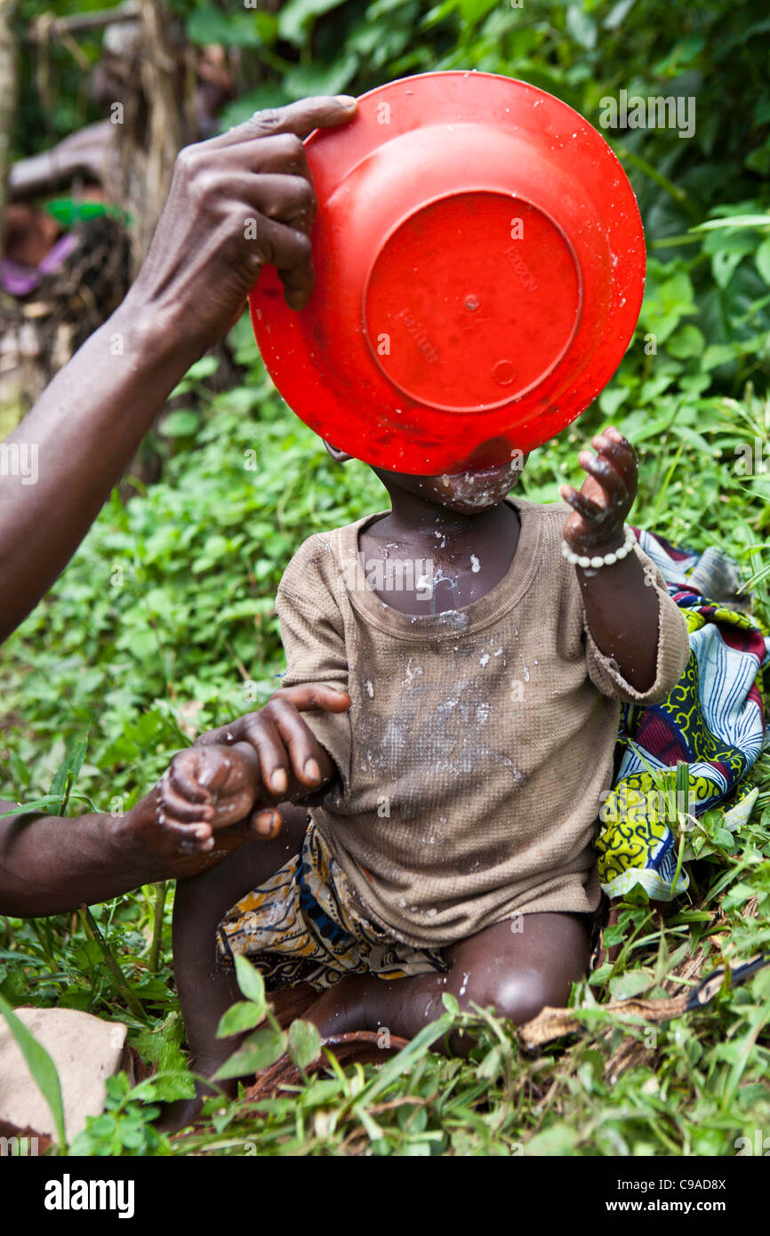 Alimentation d'un enfant du village traditionnel de Mukuno, tribu autochtone Batwa de la Forêt impénétrable de Bwindi en Ouganda. Banque D'Images