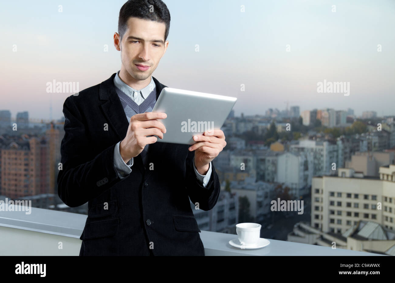 Businessman avec une tasse de café utilise une tablette numérique sur le toit d'un centre d'affaires. Banque D'Images