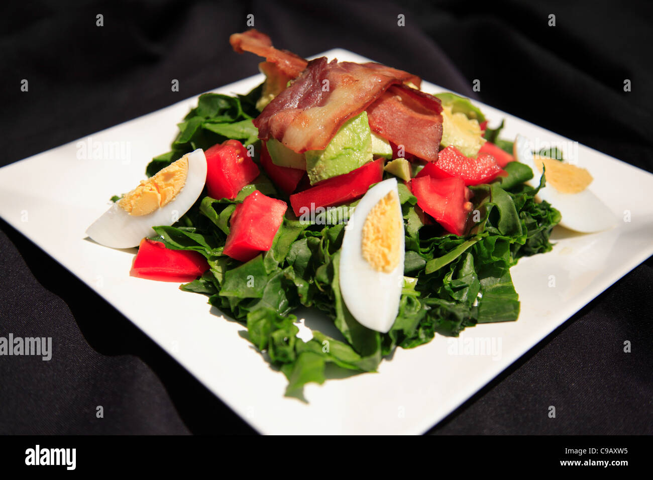 Salade d'épinards et bacon d'été sur une plaque blanche, tourné avec une faible profondeur de champ Banque D'Images